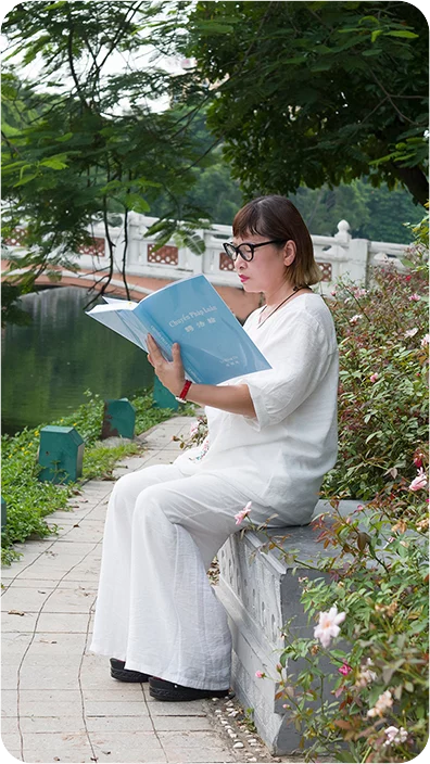 Bà Xuân Lan đang đọc sách Chuyển Pháp Luân (Ảnh nhân vật cung cấp)