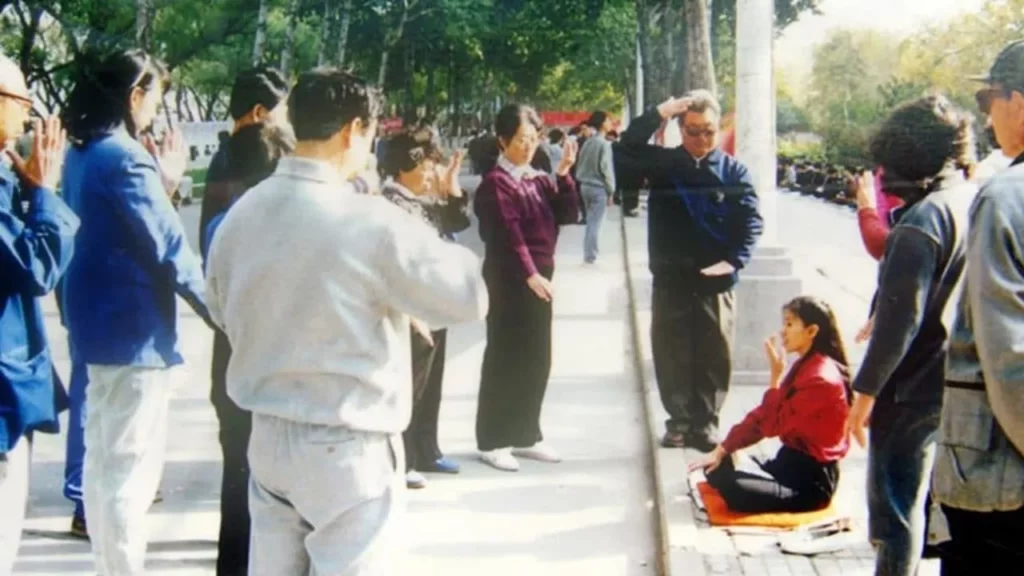 Một tình nguyện viên đang hướng dẫn các động tác tay thiền định của Pháp Luân Công cho người qua đường trên phố.