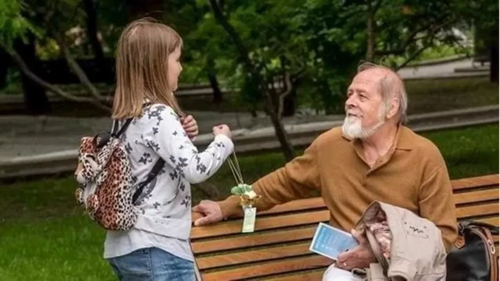 Học viên Pháp Luân Công nhỏ tuổi tặng hoa sen mang thông điệp chân tướng cho người hữu duyên. (Ảnh: Internet)