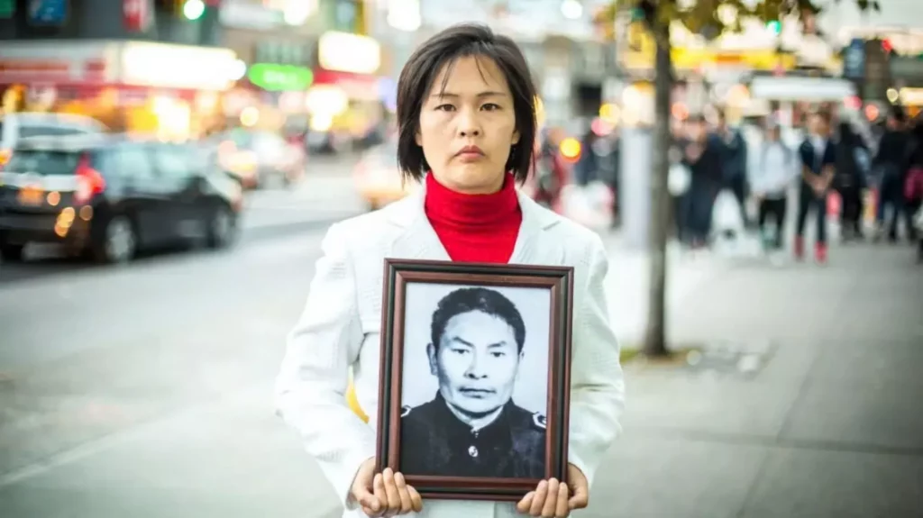 Ngày 1/11/2015, tại Flushing, Queens, New York, cô Giang Lê cầm di ảnh của cha mình. Ông đã bị ĐCSTQ giết hại vì tu luyện Pháp Luân Công. 